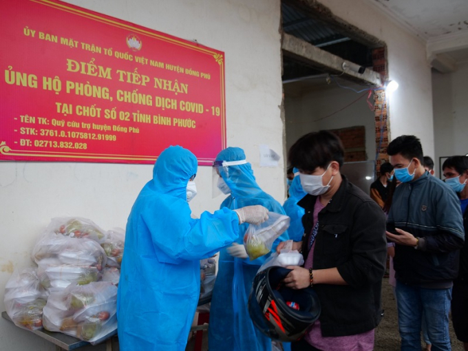 Bí thư Tỉnh Đoàn Trần Quốc Duy (bìa trái) trao suất ăn miễn phí cho các công dân Bình Phước về quê “trốn dịch” tại “nhà chờ” thuộc chốt phòng chống dịch số 2 (xã Tân Lập, H.Đồng Phú)