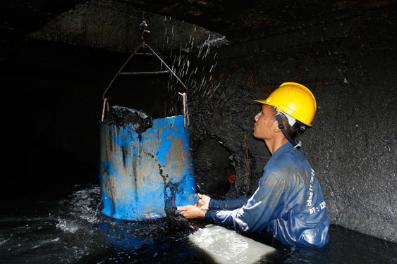 Công nhân thoát nước vớt bùn, rác dưới cống thoát nước. Ảnh: LÊ PHONG