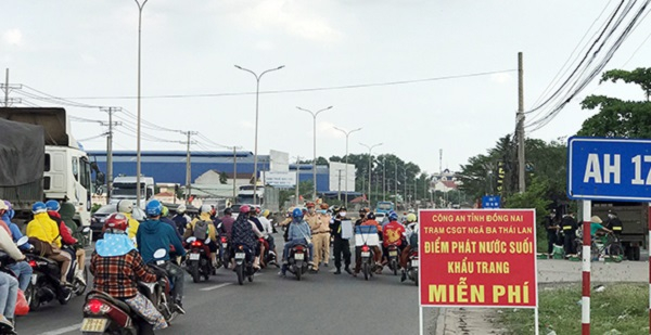 Hàng chục cán bộ chiến sĩ công an tham gia phát nước, khẩu trang cho người dân trên quốc lộ 51. (Ảnh: Trần Danh)