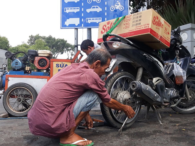 Người đàn ông lớn tuổi phá ruột xe tại điểm vá xe ở góc đường Lê Duẩn – Tôn Đức Thắng (Q.1) ẢNH: TRẦN TIẾN