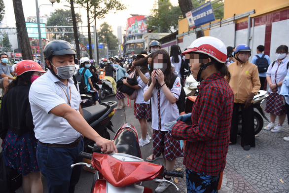 Đứng đón con tại nơi đông người nhưng vị phụ huynh này không đeo khẩu trang - Ảnh: QUANG ĐỊNH