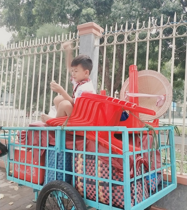 Bé Lương Gia Kiệt ngồi chơi một mình chờ mẹ sau giờ tan trường.