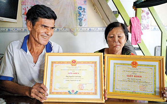 Nhận bằng khen và thư khen của tỉnh, vợ chồng ông Long chỉ cười cười rồi nói việc mình làm chẳng có gì to tát cả - Ảnh: N.TÀI