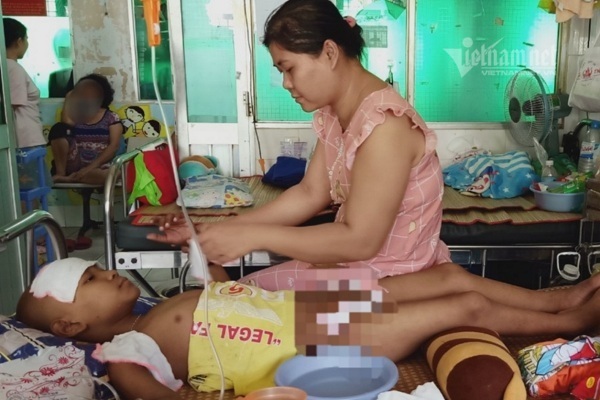 Thiên Long bị sốt cao do tác dụng phụ của thuốc hóa chất, chị Vân phải lau thường xuyên để hạ sốt cho con.