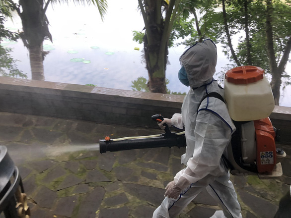 Nhân viên y tế phun xịt thuốc khử khuẩn nhà hàng Hương Phù Sa - Ảnh: N.N.