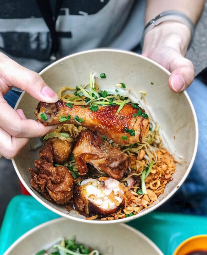 Tô hủ tiếu mì nổi bật với sợi dai, màu vàng hấp dẫn. Điểm nhấn là phần topping chất lượng gồm tôm, bò viên, hoành thánh chiên, trứng cút và thịt gà quay được tẩm ướp đậm đà. Mức giá dao động 40.000-60.000 đồng. Điểm trừ là chỗ ngồi ở quán khá hạn chế. Ảnh: Ruahaman.