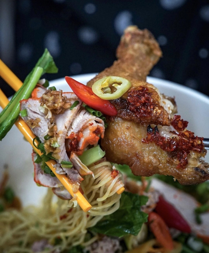 Mì xá xíu gà chiên là món ngon mà bạn có thể thưởng thức tại quán ở đường Cao Đạt, quận 5. Phần ăn được chuẩn bị bắt mắt với sợi mì vàng ươm, thịt xá xíu và gà chiên thơm lừng. Ớt, hành ăn kèm cũng góp phần tạo sắc màu cuốn hút. Ngoài ra, thực đơn của tiệm còn có mì sườn kho sủi cảo thơm béo, lạ miệng không kém. Mức giá từ 50.000 đồng/tô. Ảnh: Foodholicvn.