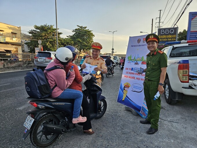 Người dân nhận nước, khăn lạnh cùng tờ rơi tuyên truyền pháp luật tại  “Trạm tiếp sức” của Trạm CSGT Tân Túc  