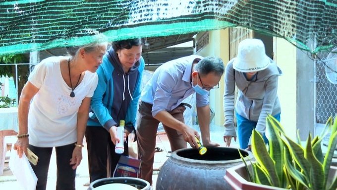 Cán bộ y tế của thành phố kiểm tra và hướng dẫn người dân tại xã Hòa An loại bỏ nước trong các dụng cụ có thể chứa lăng quăng