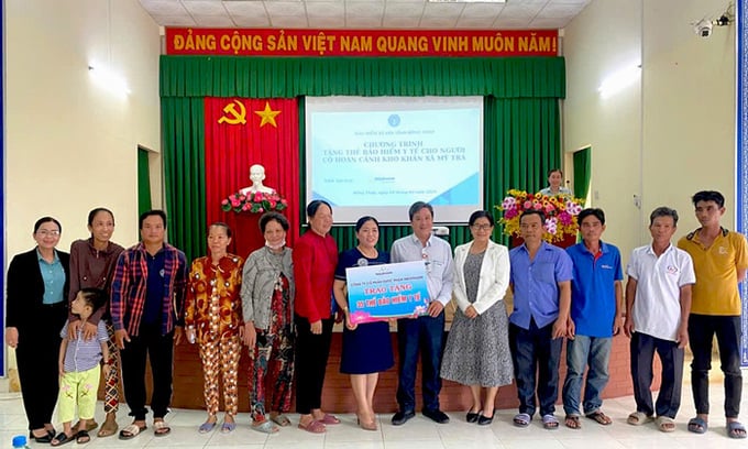 Đại diện bảo hiểm xã hội cùng các nhà tài trợ tặng thẻ Bảo hiểm y tế cho người dân (Ảnh: Phạm Thọ)